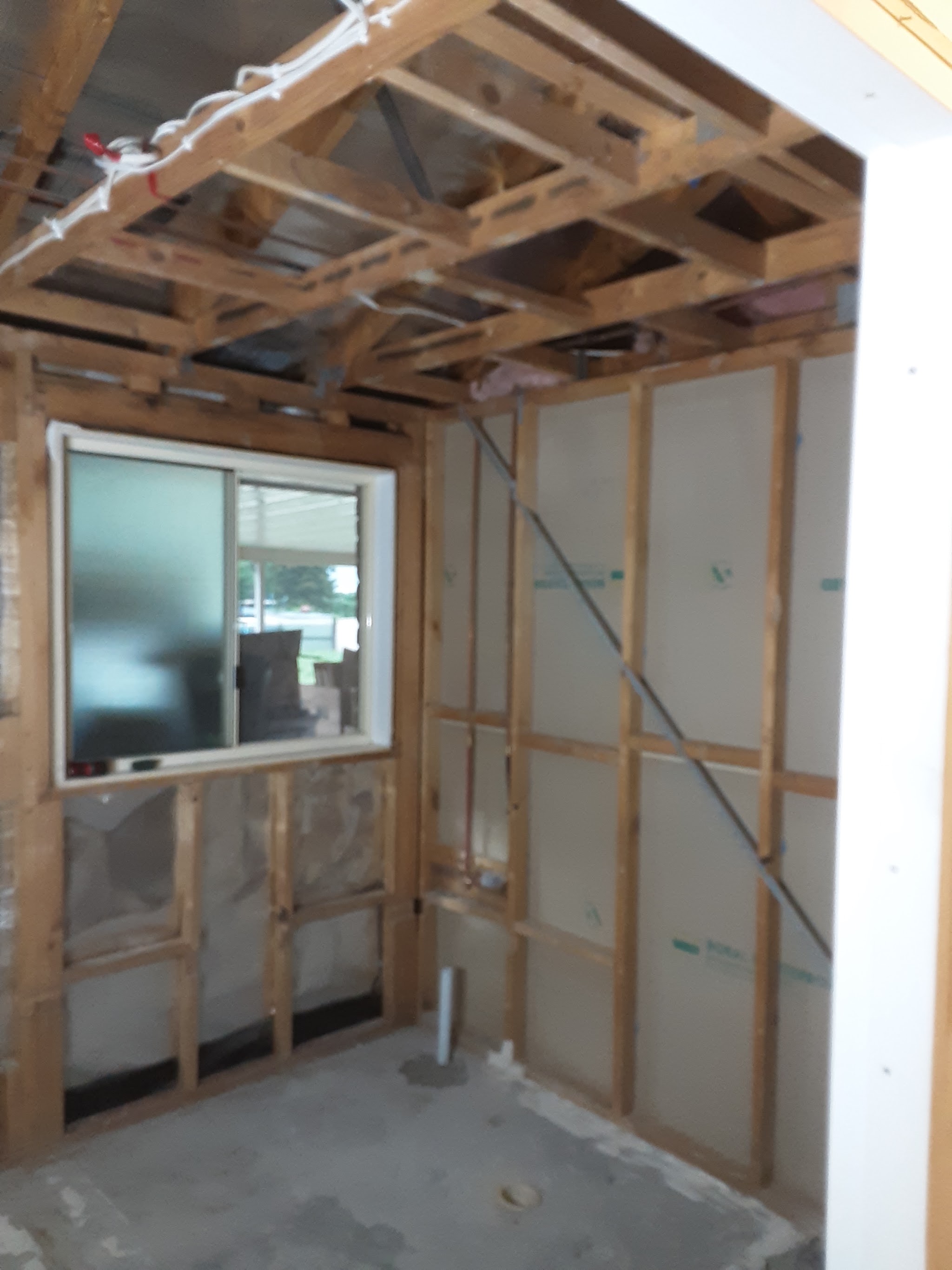 A room stripped back to exposed timber roof trusses with new sheeting started on one wall