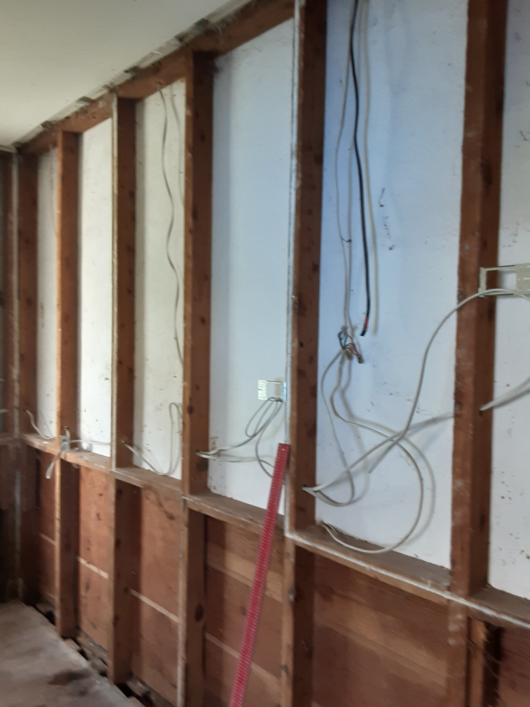 An old internal wall stripped back to the studs with the existing wiring exposed