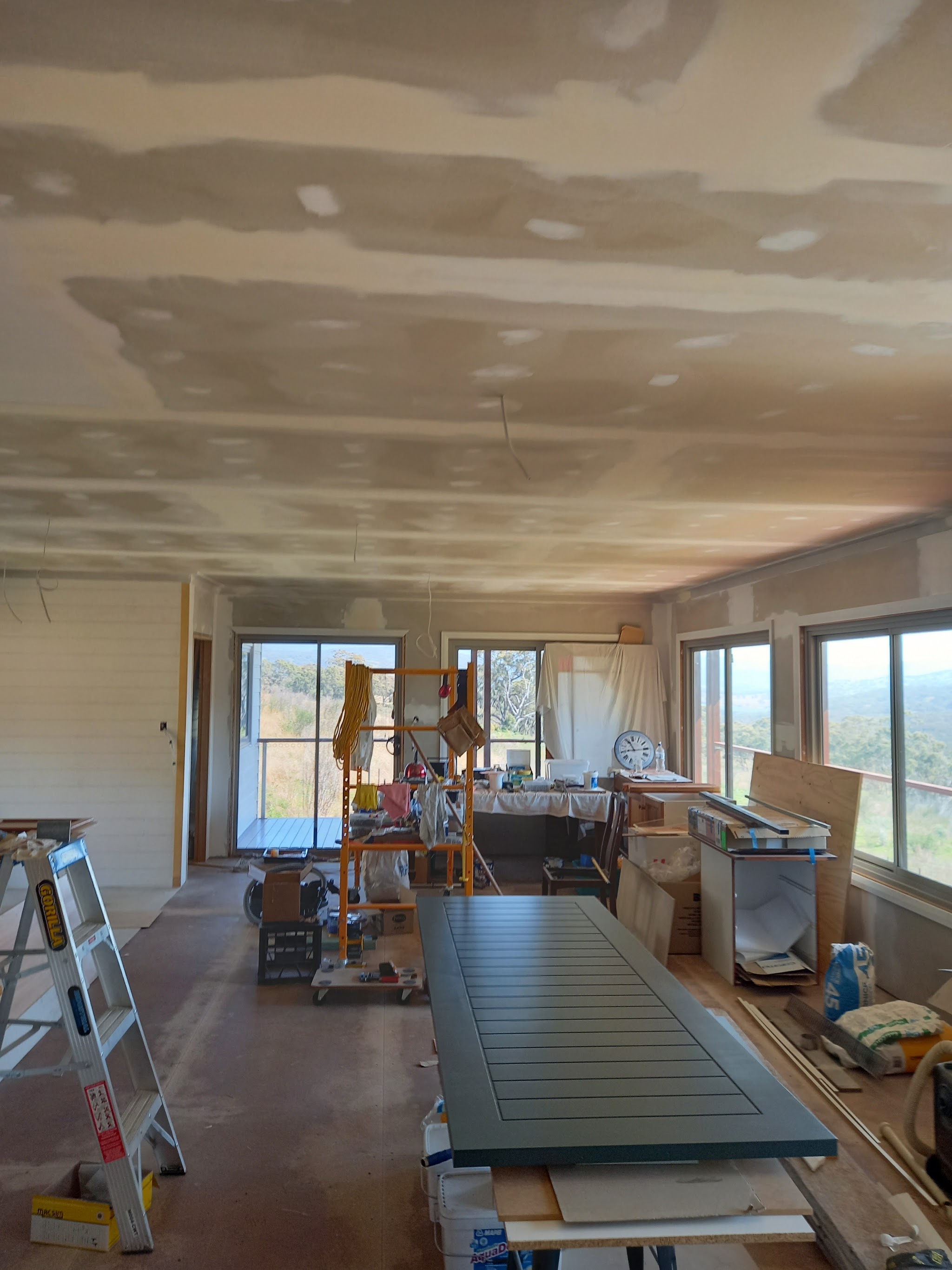 A country home mid renovation with the ceiling set and paddocks visible through the windows