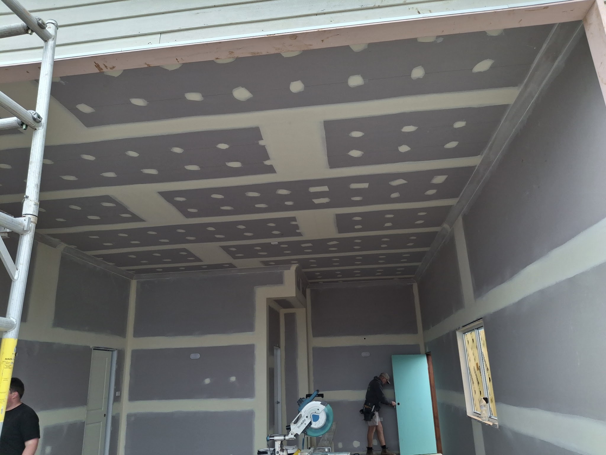 Two of the Lancaster Plastering team working inside a new build with the walls and ceiling already set and sanded